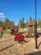 kuvassa pienemmille lapsille suunniteltu leikkialue, jossa pieni mökki, liukumäki ja leppäkerttukeinu